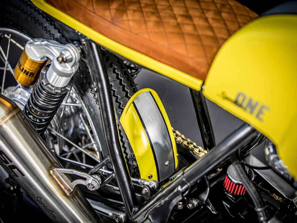 gelbes Custom Motorrad Speedbox One Studioaufnahme Ledersattel und SC Project Auspuff mit Logo