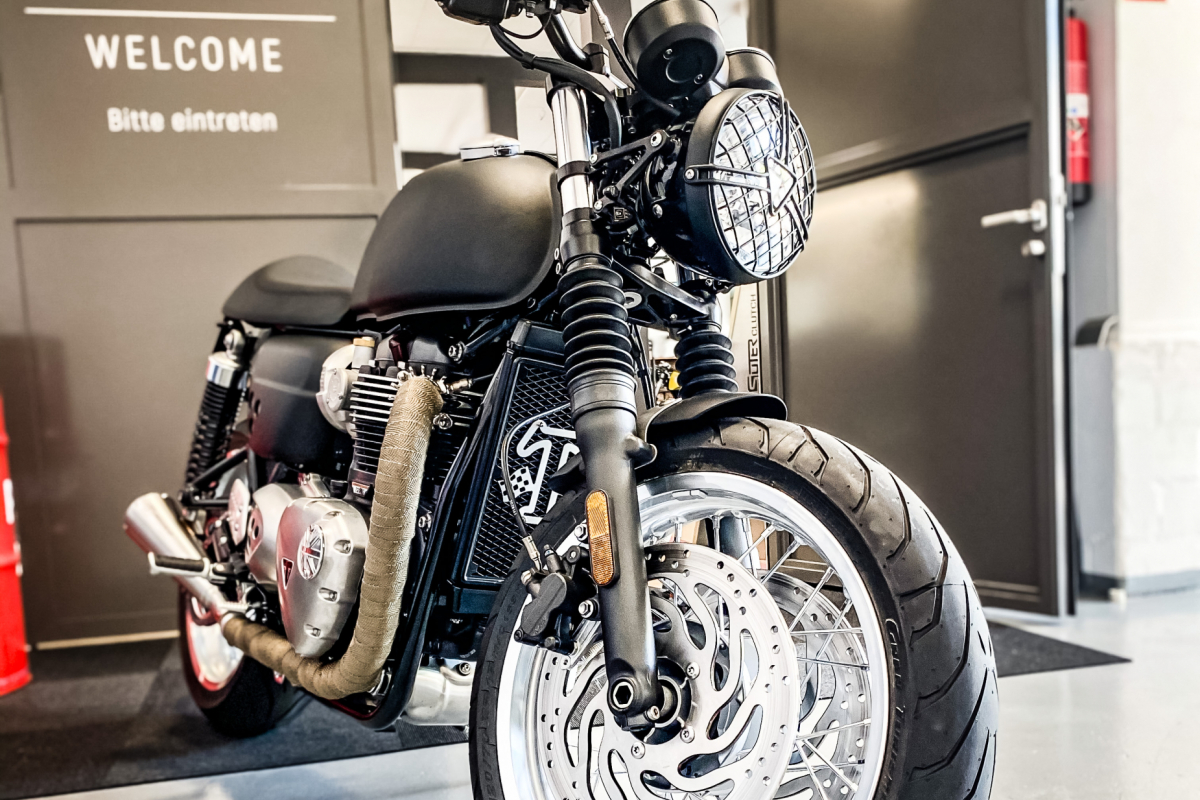 Triumph Thruxton Schwarz vor dem Showroom mit Seitenspiegel – Customizing Motorrad